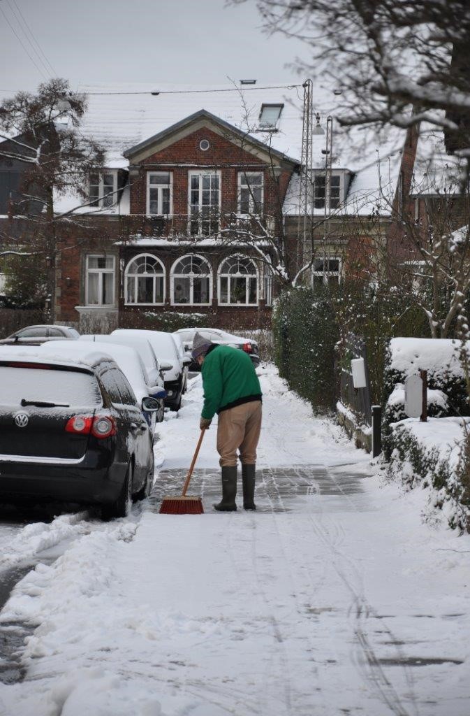 Mand der rydder sne på fortov